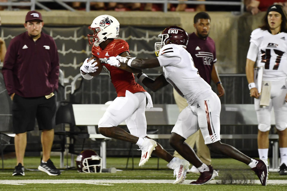 Louisville wide receiver Ahmari Huggins-Bruce, front left, runs from the grasp of Eatern Kentucky defensive back Joseph Sayles, front right, during the second half of an NCAA college football game in Louisville, Ky., Saturday, Sept. 11, 2021. (AP Photo/Timothy D. Easley)