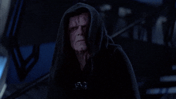 Emperor Palpatine, a character from Star Wars, wearing a dark hooded robe. His face appears disfigured while he is standing in a dimly lit environment