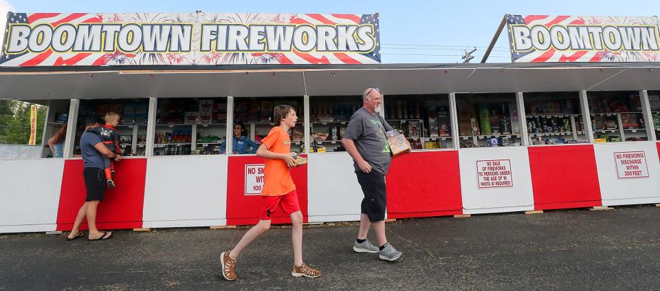 Jeff Gabel, of Belfair, right, and his grandson Michael Burhart, 10, carry their fireworks to their car after visiting the Boomtown Fireworks stand in East Bremerton on Thursday.