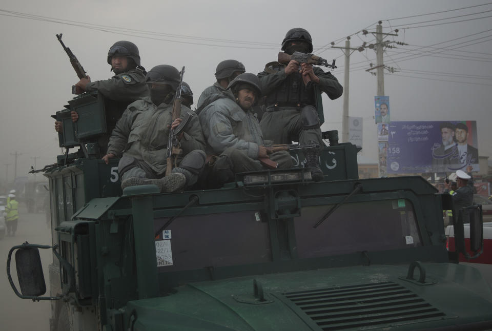 Afghan policemen ride on top of their armored vehicle as they rush to the scene as Taliban militants attacked the main Afghan election commission's headquarters in the outskirts of Kabul, Afghanistan, firing on the compound with rocket-propelled grenades and heavy machine guns from a house outside its perimeter wall, Saturday, March 29, 2014. Dozens of employees and other people who had been inside the Independent Election Commission compound took cover in the basement, and no casualties were reported. But two warehouses were hit and set on fire, witnesses said. (AP Photo/Anja Niedringhaus)