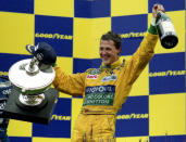 FILE - In this Aug. 30, 1992 file photo, German Formula One racing driver Michael Schumacher holds the trophy and magnum bottle of champagne, after winning his first Grand Prix race in Francorchamps, Belgium. British driver Lewis Hamilton made Formula One history on Sunday, Oct. 25, 2020 winning the Portuguese Grand Prix for a 92nd win to move one ahead of German great Michael Schumacher. (AP Photo/Roberto Pfeil, file)