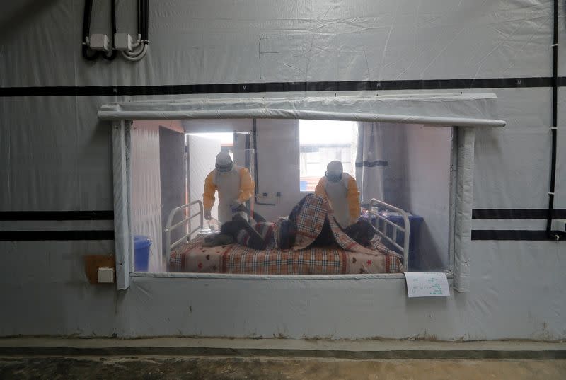 FILE PHOTO: Moise Vaghemi, 33, (L) an Ebola survivor who works as a nurse cares for a patient who is suspected to be suffering from Ebola, inside the Biosecure Emergency Care Unit (CUBE) at the Ebola treatment centre in Katwa