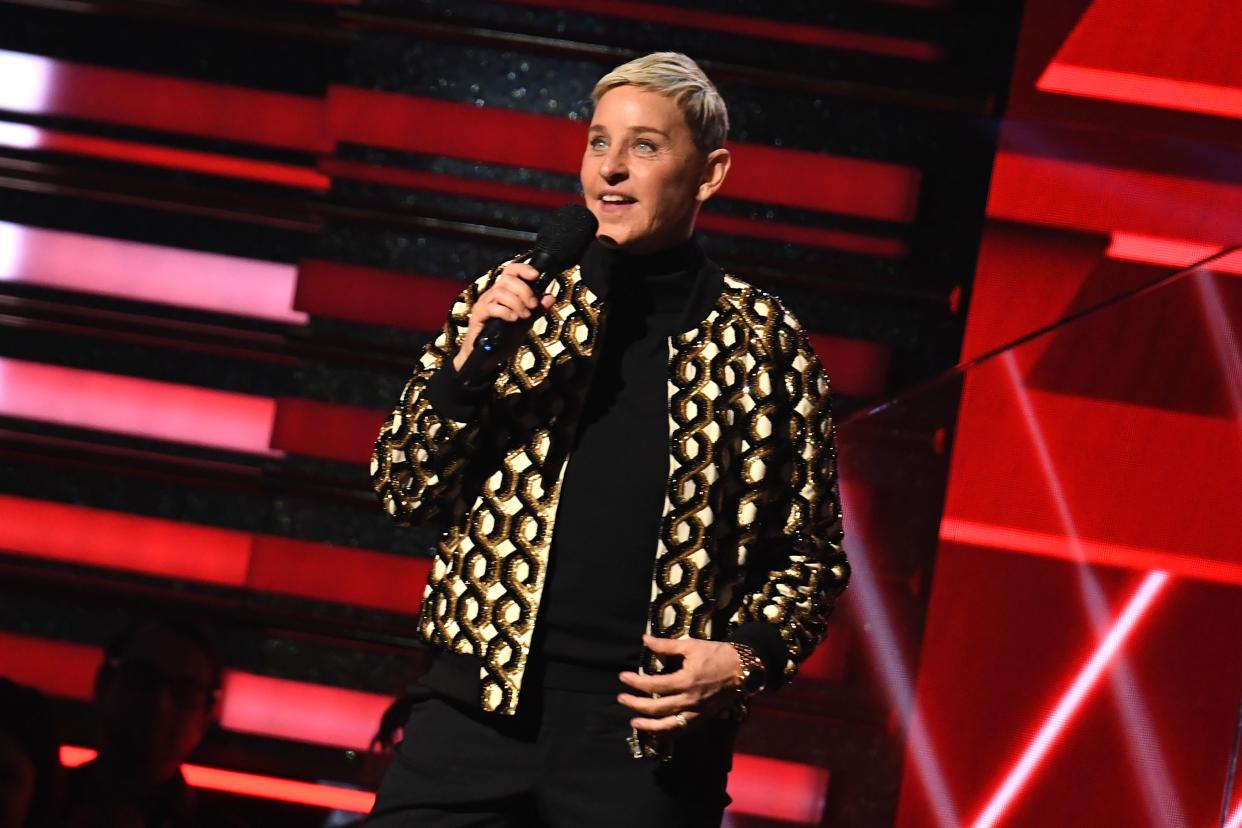 Ellen DeGeneres holds a microphone onstage.