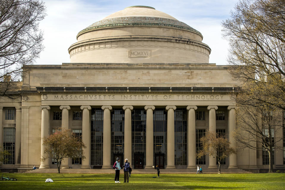 People stand on the lawn outside Building 10 on the Massachusetts Institute of Technology (MIT) campus in Cambridge, Mass. on Monday, April 20, 2020. (Adam Glanzman/Bloomberg via Getty Images)