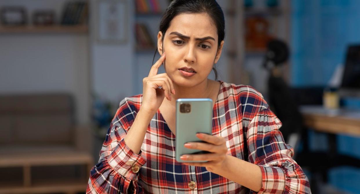 Woman looking confused at phone, to represent digital dementia. (Getty Images)