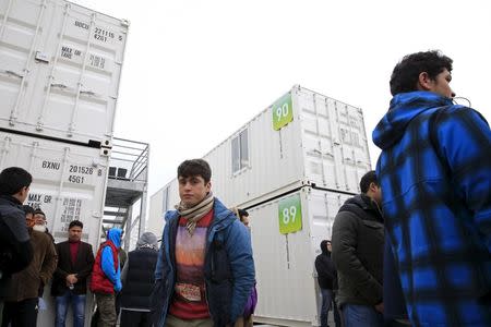 Migrants stand amidst shipping containers converted into homes at a state-run shelter near Calais, northern France, February 21, 2016. REUTERS/Pascal Rossignol