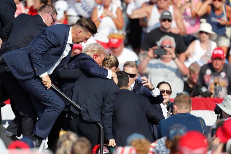 Trump is rushed off stage by Secret Service agents after the shooting (EPA)