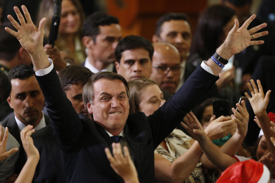 Brazil's President Jair Bolsonaro waves tot he crowd during a Christmas celebration with staff and students at the Planalto Presidential Palace, in Brasilia, Brazil, Thursday, Dec. 19, 2019. (AP Photo /Eraldo Peres)