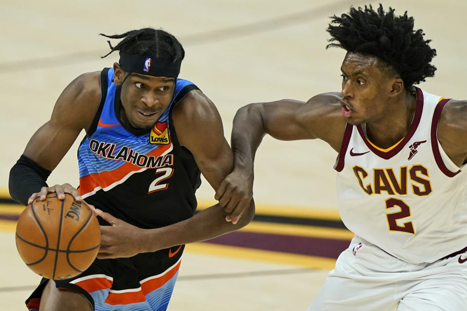 Oklahoma City Thunder's Shai Gilgeous-Alexander, left, drives past Cleveland Cavaliers' Collin Sexton in the second half of an NBA basketball game, Sunday, Feb. 21, 2021, in Cleveland. (AP Photo/Tony Dejak)