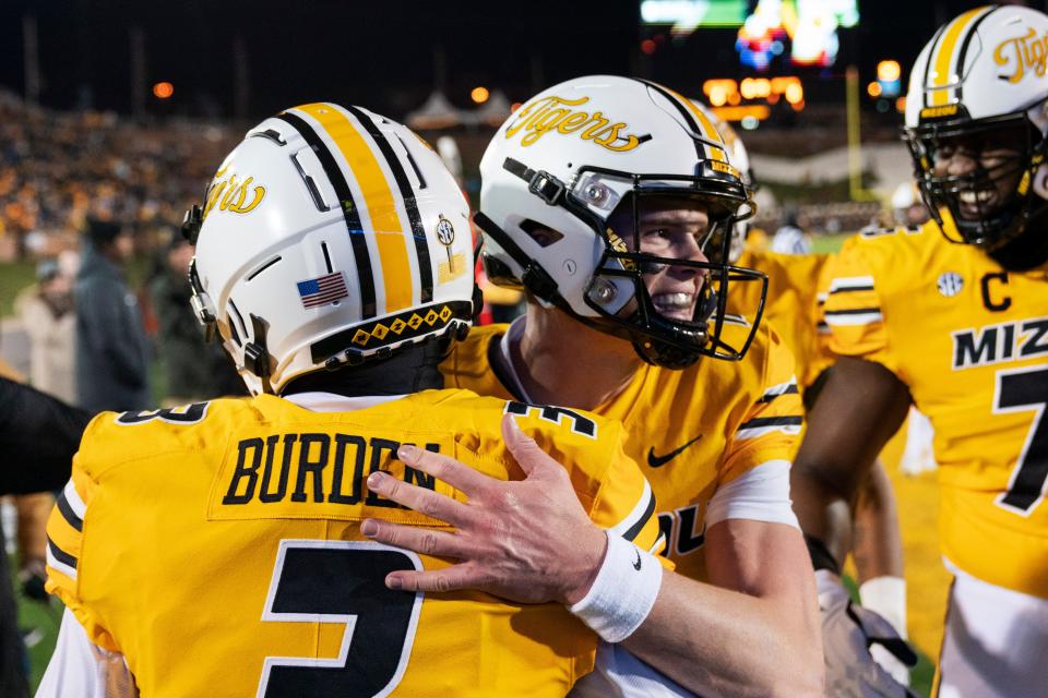 Missouri quarterback Brady Cook, center, hugs Luther Burden, left, after Burden scored a touchdown during the first quarter of the team's NCAA college football game against New Mexico State Saturday, Nov. 19, 2022, in Columbia, Mo.