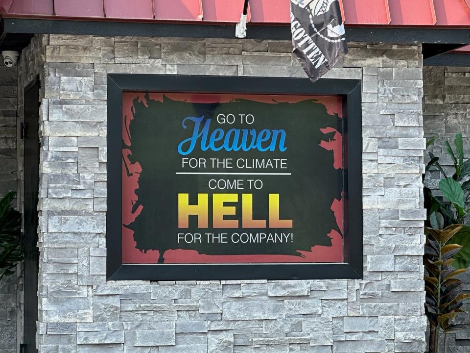 Sign on building that says "Go to heaven for the climate come to Hell for the company"