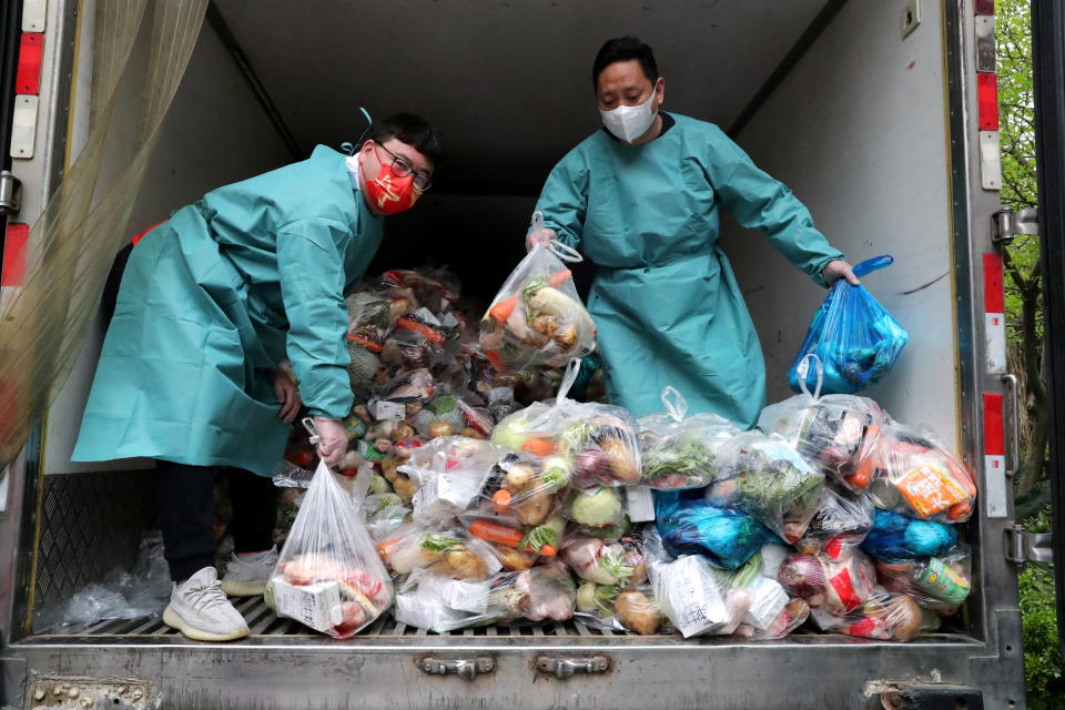 Workers wearing protective gear sort bags of vegetables and groceries to distribute to residents in Shanghai 