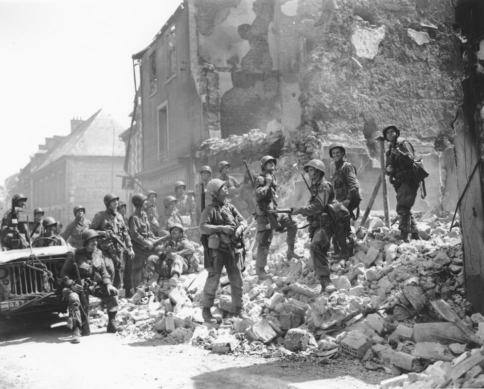 FILE - U.S. soldiers stand on the remains of a house as they inspect damage in Carentan, in the Normandy region of France, June 15, 1944. The 80th anniversary this week of D-Day is a mixed bag of emotions for French survivors of the Battle of Normandy. They remain eternally grateful for their liberation from Nazi occupation in World War II but cannot forget its steep cost in French lives. (AP Photo/Peter Carroll, File)