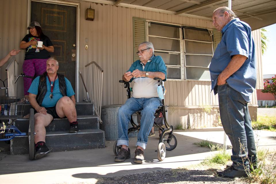 Residents Alondra Ruiz, Robert Chastain, Gerald Suter and Ray Bernier gather outside Suter's home at the Periwinkle Mobile Home Park in Phoenix on May 19, 2022.