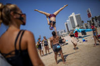 Acrobats perform as they wear face masks during a protest against government's decision to close beaches during the three-week nationwide lockdown due to the coronavirus pandemic, in Tel Aviv, Israel, Saturday, Sept 19, 2020. Israel went back into a full lockdown on Friday to try to contain a coronavirus outbreak that has steadily worsened for months as its government has been plagued by indecision and infighting. (AP Photo/Oded Balilty)