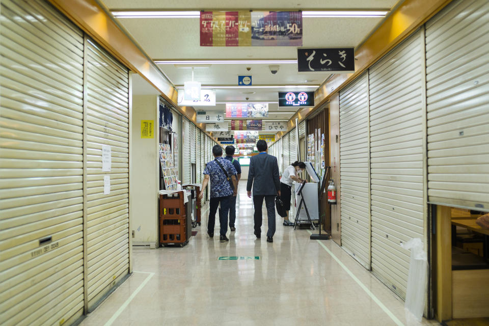 Men walk on the floor of a multi-tenant building, with most of the tenants already shut down before 8 p.m., the closing time suggested by the government for the ongoing state of emergency in Tokyo, Thursday, Sept. 30, 2021. On Friday, Oct. 1, 2021, Japan fully came out of a coronavirus state of emergency for the first time in more than six months as the country starts gradually easing virus measures to help rejuvenate the pandemic-hit economy as the infections slowed.(AP Photo/Hiro Komae)
