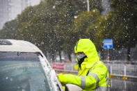 In this photo released by China's Xinhua News Agency, a traffic policeman wearing a face mask checks a car during a snowfall in Xiaogan in central China's Hubei Province, Saturday, Feb. 15, 2020. The virus is thought to have infected more than 67,000 people globally and has killed at least 1,526 people, the vast majority in China, as the Chinese government announced new anti-disease measures while businesses reopen following sweeping controls that have idled much of the economy. (Hu Huhu/Xinhua via AP)