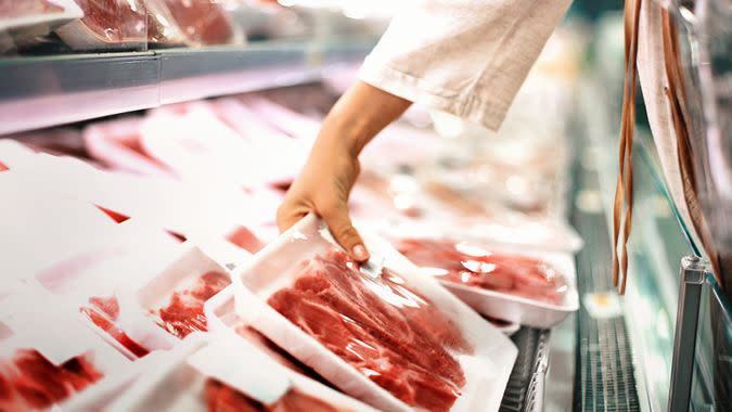 Closeup side view of unrecognizable woman chossing some fresh meat at local supermarket.