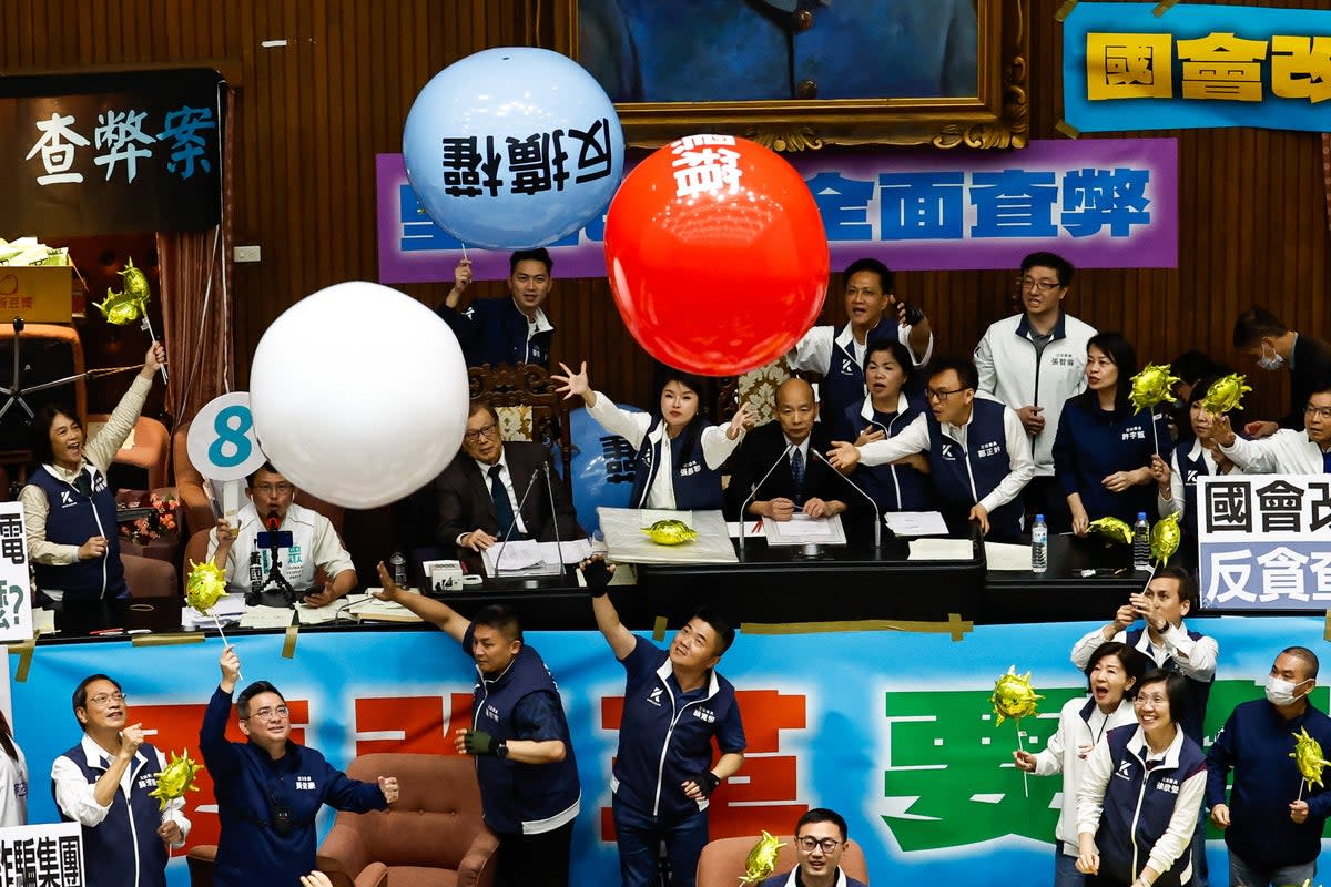 Taiwanese lawmakers from the Democratic Progressive Party throw inflatable balloons with words reading ‘anti evil laws’ at the Parliament President Han Kuo-yu, at the chamber inside the Legislative Yuan, in Taipei, Taiwan (EPA)