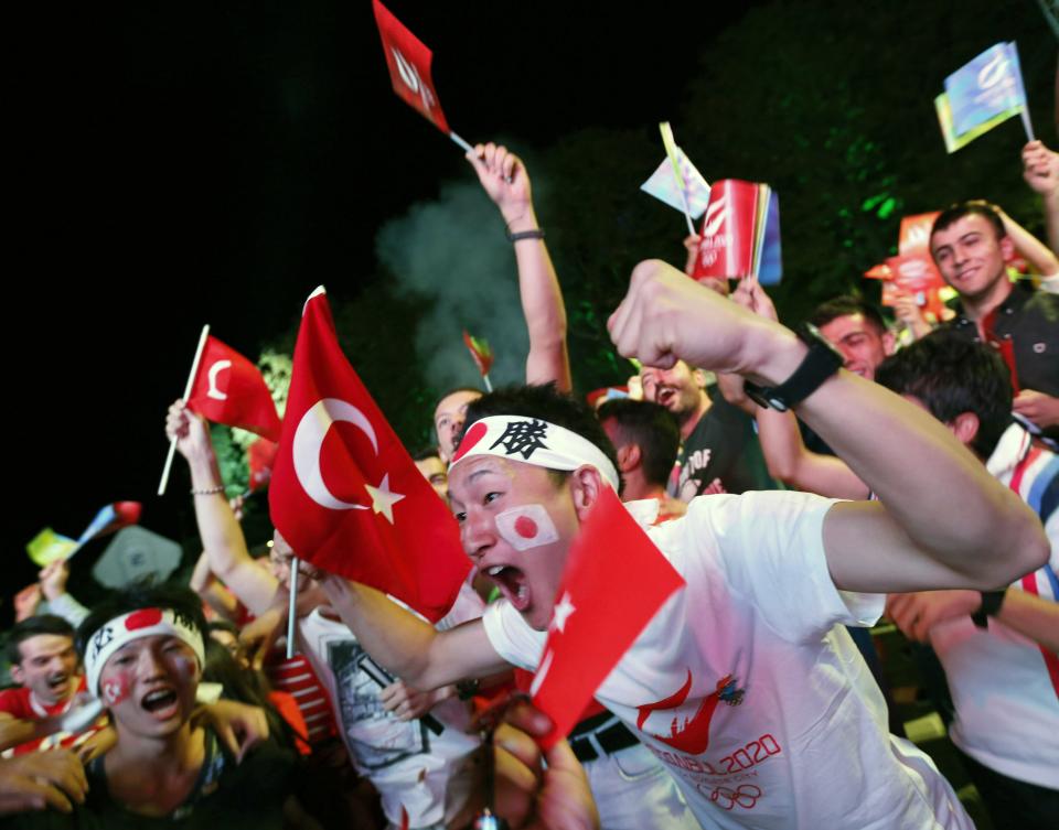 Turks and Japanese tourists visiting Turkey celebrate the results of the opening round of voting for the city will host the 2020 summer Games as they watch it live on big screens in Sultanahmet Square in Istanbul September 7, 2013. Either Tokyo or Istanbul will host the 2020 summer Games after the International Olympic Committee voted on Saturday. A third candidate, Madrid, was eliminated in the opening round of voting before the IOC selected one of the remaining two cities in a secret ballot. REUTERS/Murad Sezer (TURKEY - Tags: SPORT OLYMPICS)