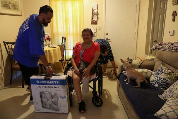 PHOTO: Jon David De Leon, with the non-profit Eagles Flight Advocacy and Outreach, delivers a fan to Juanita Alarcon at Col. George Cisneros Apartments, a senior apartment complex, to help cope with the heat in San Antonio, Texas, July 11, 2022. (Stringer/Reuters)