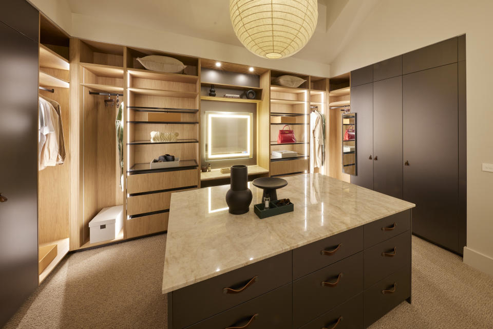 A wide shot of the walk-in robe with a large island in the middle and shelving all around