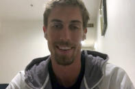 In this frame from video during a call with The Associated Press, beach volleyball player Taylor Crabb, of the United States, talks Saturday, July 24, 2021, about being forced to withdraw from the Olympics after testing positive for COVID-19 when he arrived to compete in the 2020 Summer Olympics in Tokyo, Japan. The first-time Olympian has been stuck in a quarantine hotel for more than 23 hours each day, occupying himself by playing cribbage and doing yoga with friends and family over FaceTime. (Courtesy of Taylor Crabb via AP)