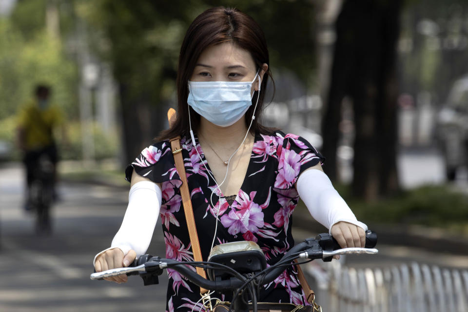 A woman wearing a mask to curb the spread of the new coronavirus rides an electric bike on the streets of Beijing on Friday, June 19, 2020. China declared a fresh outbreak in Beijing under control after numbers for new cases stabilized as hundreds of thousands are tested. (AP Photo/Ng Han Guan)