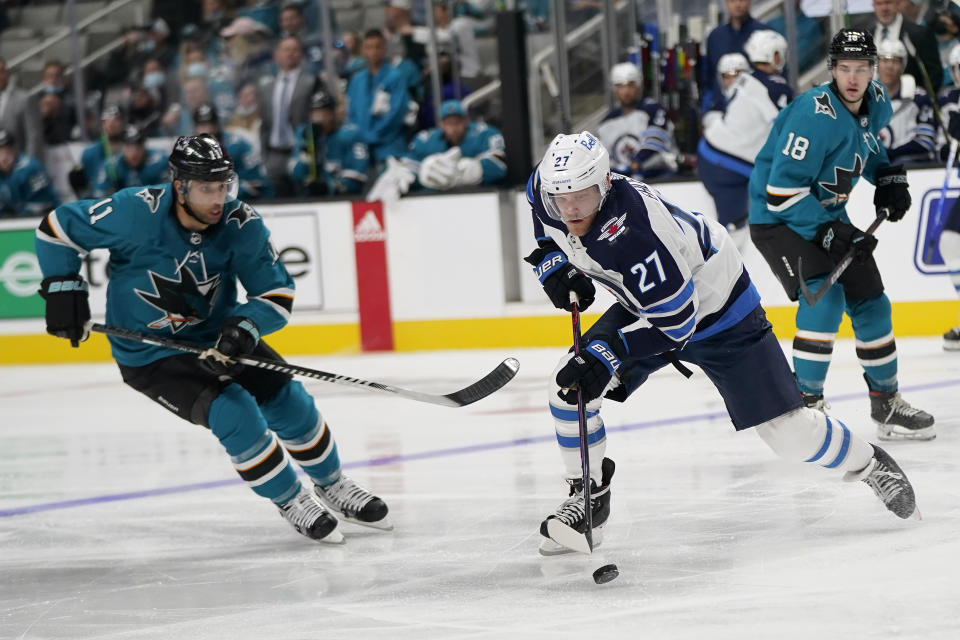 Winnipeg Jets left wing Nikolaj Ehlers (27) skates with the puck against San Jose Sharks center Andrew Cogliano (11) during the second period of an NHL hockey game in San Jose, Calif., Saturday, Oct. 16, 2021. (AP Photo/Jeff Chiu)