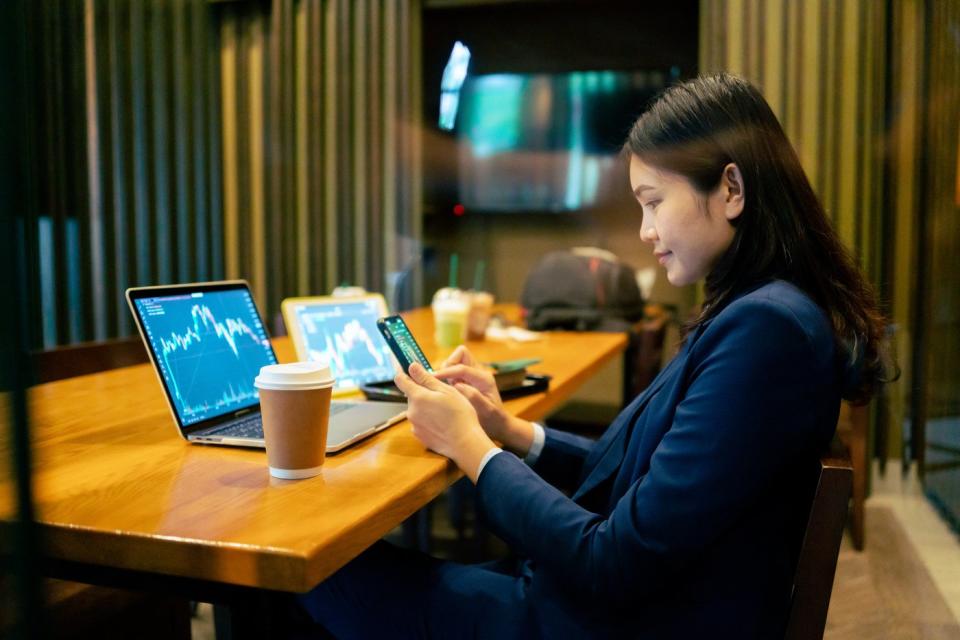 Person looking at stock charts on phone and computers.