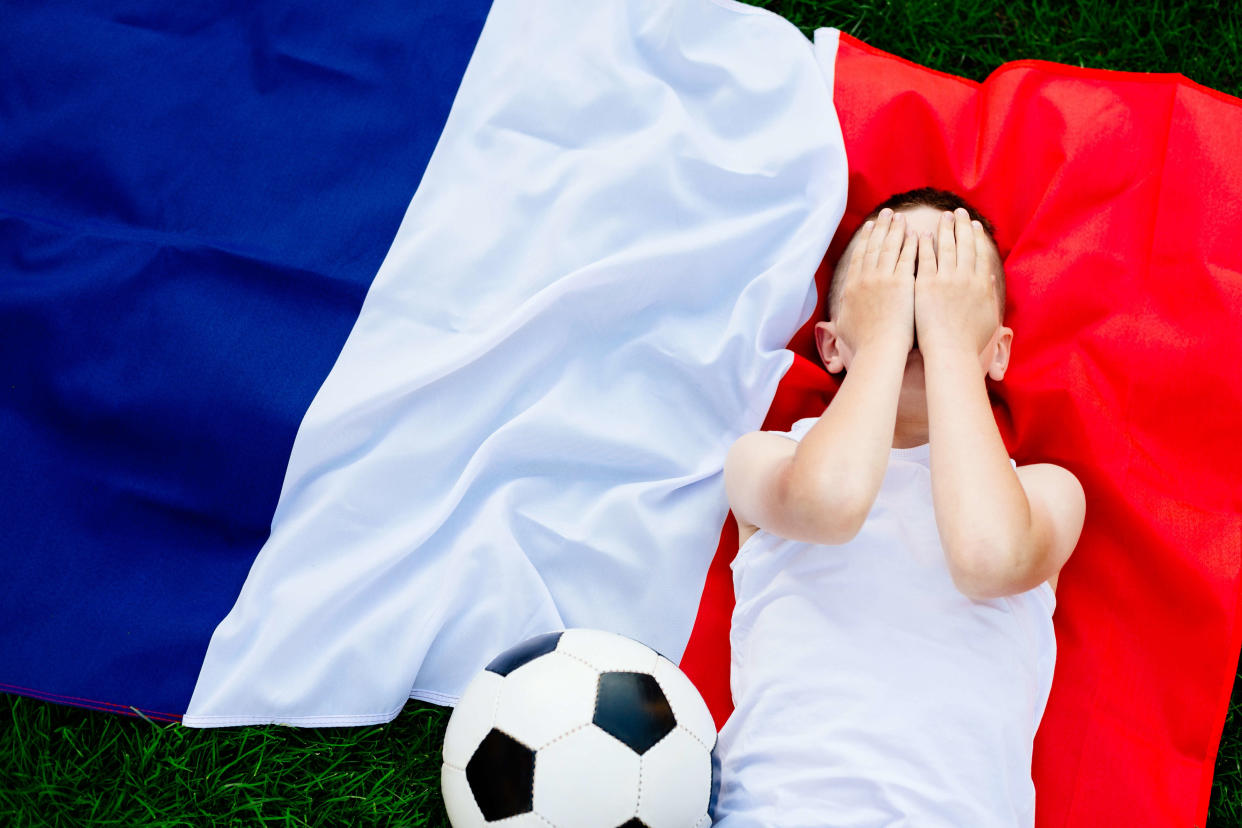 Disappointed France national football team. Child boy with football ball and French flag