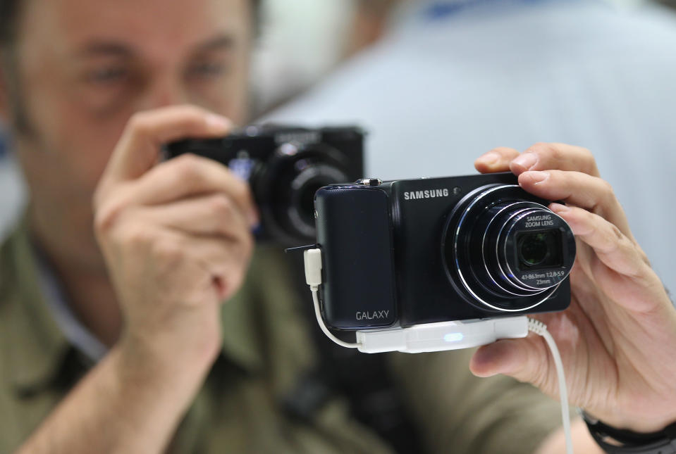 BERLIN, GERMANY - AUGUST 30: A visitor tries out the new Samsung Galaxy Camera, which combines a smartphone and a digital camera with a zoom lens, during a press day at the Samsung stand at the IFA 2012 consumer electronics trade fair on August 30, 2012 in Berlin, Germany. IFA 2012 will be open to the public from August 31 through September 5. (Photo by Sean Gallup/Getty Images)