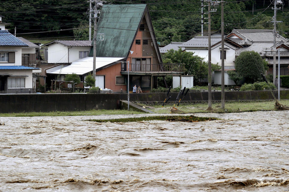 People look at swollen Hida river following heavy rain in Gero, Gifu prefecture, southern Japan Wednesday, July 8, 2020. Floodwaters flowed down streets in southern Japanese towns hit by heavy rains. (Yuya Shino/Kyodo News via AP)