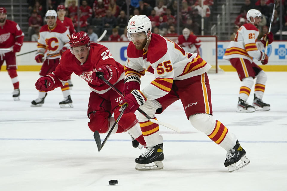 Detroit Red Wings center Mitchell Stephens (22) pressures Calgary Flames defenseman Noah Hanifin (55) in the second period of an NHL hockey game Thursday, Oct. 21, 2021, in Detroit. (AP Photo/Paul Sancya)
