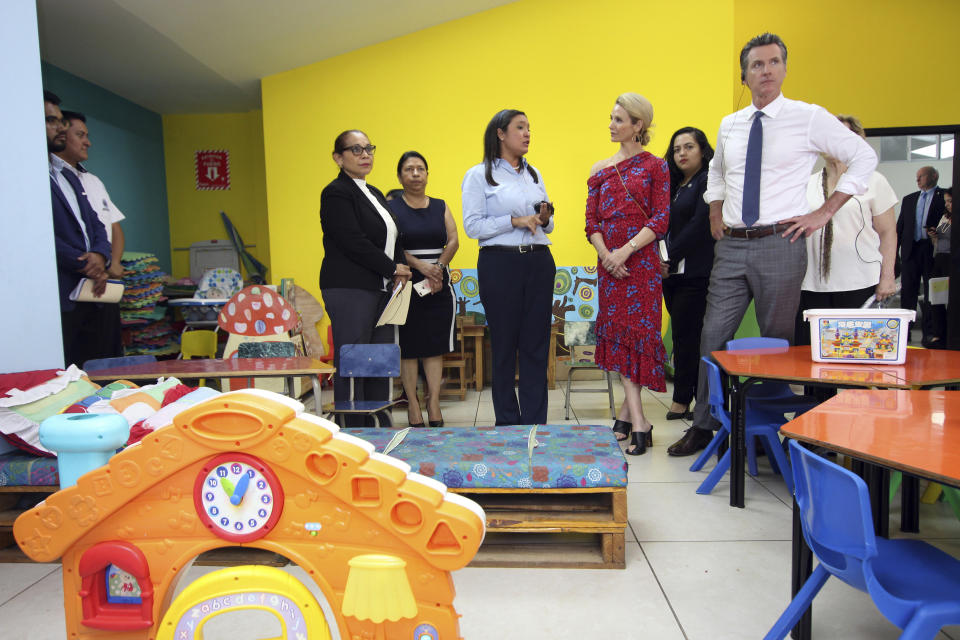 California Gov. Gavin Newsom, right, with his wife, Jennifer Siebel Newsom, listen to Ana Solorzano, head of the Department for Migrant Care, DGME, center, in El Salvador, during their visit at La Chacra Immigration Center in San Salvador, El Salvador, Monday, April 8, 2019. (AP Photo/Salvador Melendez)