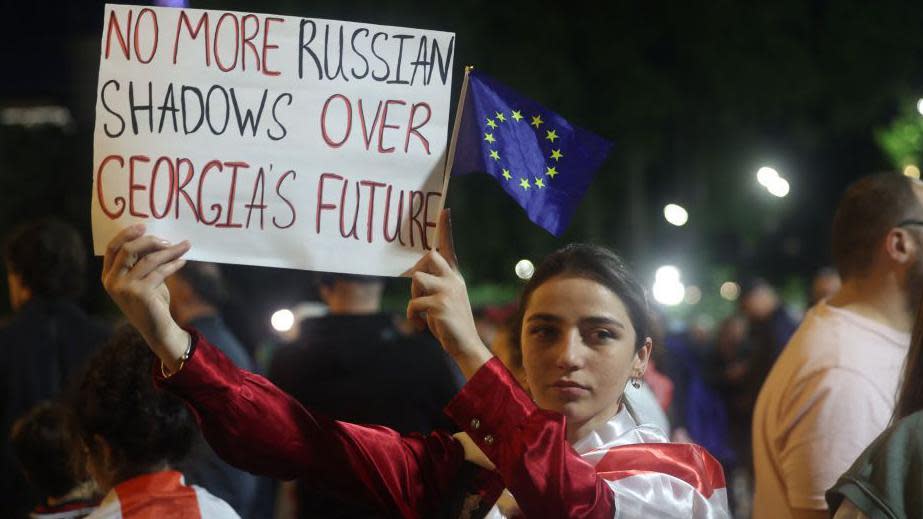 Protester holds sign reading "No more Russian shadows over Georgia's future"