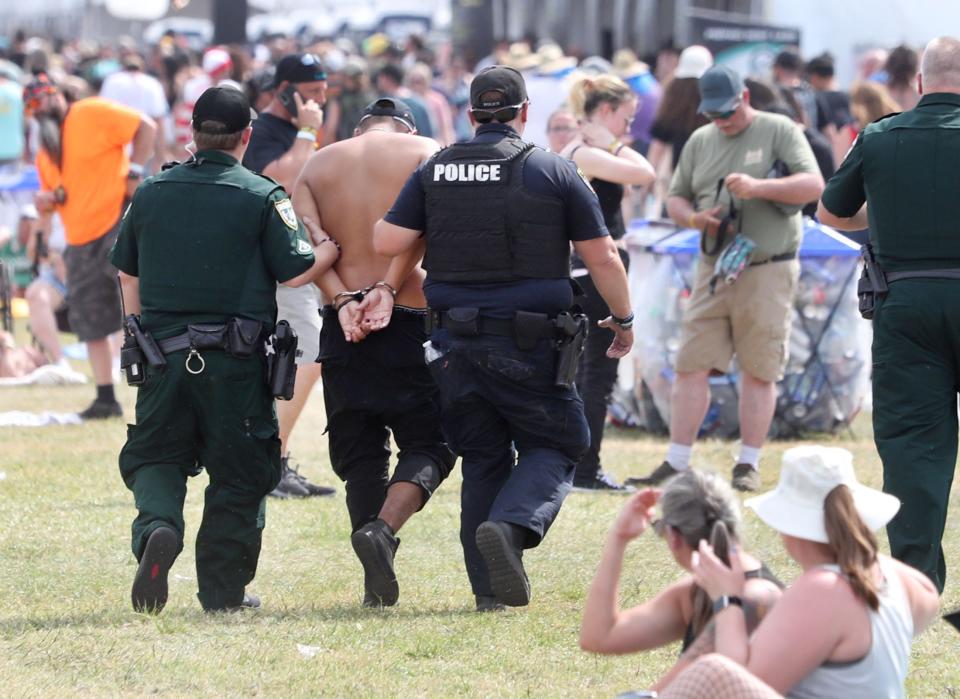 Law inforcement escorts a fan in cuffs, Friday May 10, 2024 during Welcome To Rockville at Daytona International Speedway.