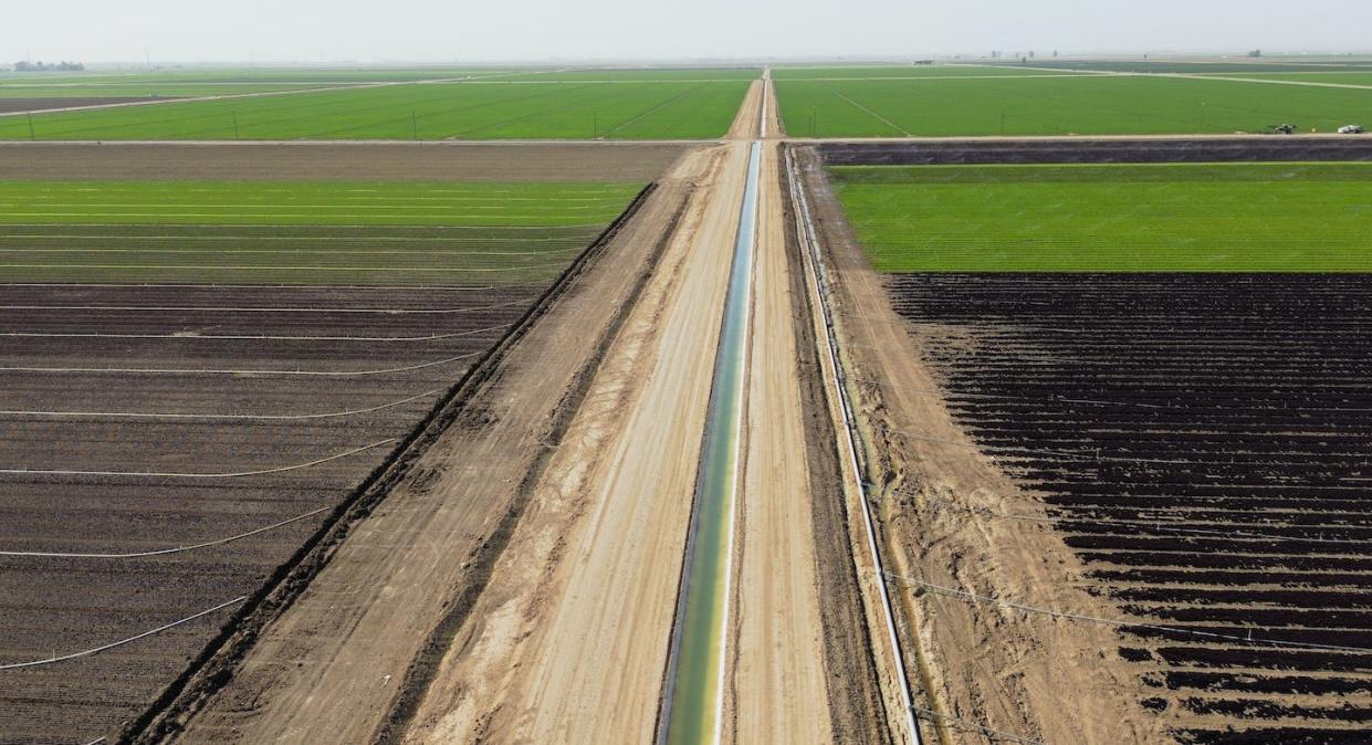 An irrigation canal moves Colorado River water through farm fields in California's Imperial Valley. <a href="https://www.gettyimages.com/detail/news-photo/this-aerial-view-shows-an-irrigation-canal-through-news-photo/1248577568" rel="nofollow noopener" target="_blank" data-ylk="slk:Photo by Sandy Huffaker / AFP via Getty Images;elm:context_link;itc:0;sec:content-canvas" class="link ">Photo by Sandy Huffaker / AFP via Getty Images</a>
