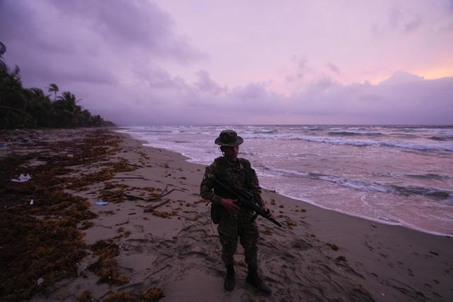 A Panamanian border officer stands guard on a beach as members of The Leatherback Project look for turtles near Armila, Panama, Saturday, May 20, 2023. Panama's president signed a law in March recognizing the rights of sea turtles. (AP Photo/Arnulfo Franco)