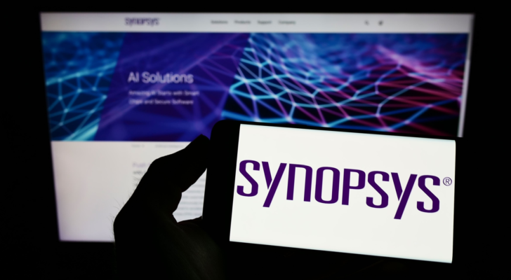 Person holding mobile phone with logo of American technology company Synopsys Inc. (SNPS) on screen in front of web page. Focus on phone display. Unmodified photo.