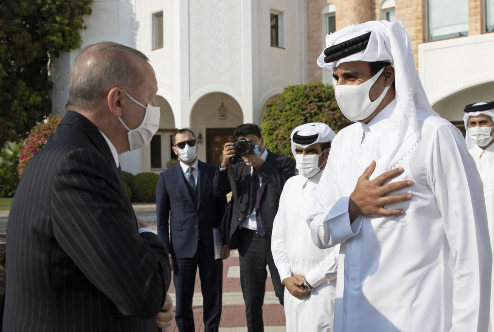 In this photo released by the Qatar Amiri Diwan, Turkish President Recep Tayyip Erdogan, left, is welcomed by Emir of Qatar Sheikh Tamim bin Hamad Al Thani, after his arrival in Doha, Qatar, Wednesday, Oct. 7, 2020. (Qatar Amiri Diwan via AP)