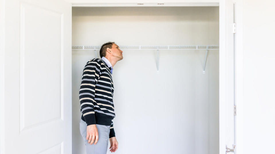 Young man checking looking inside small closet in new room after or before moving in, during open house.