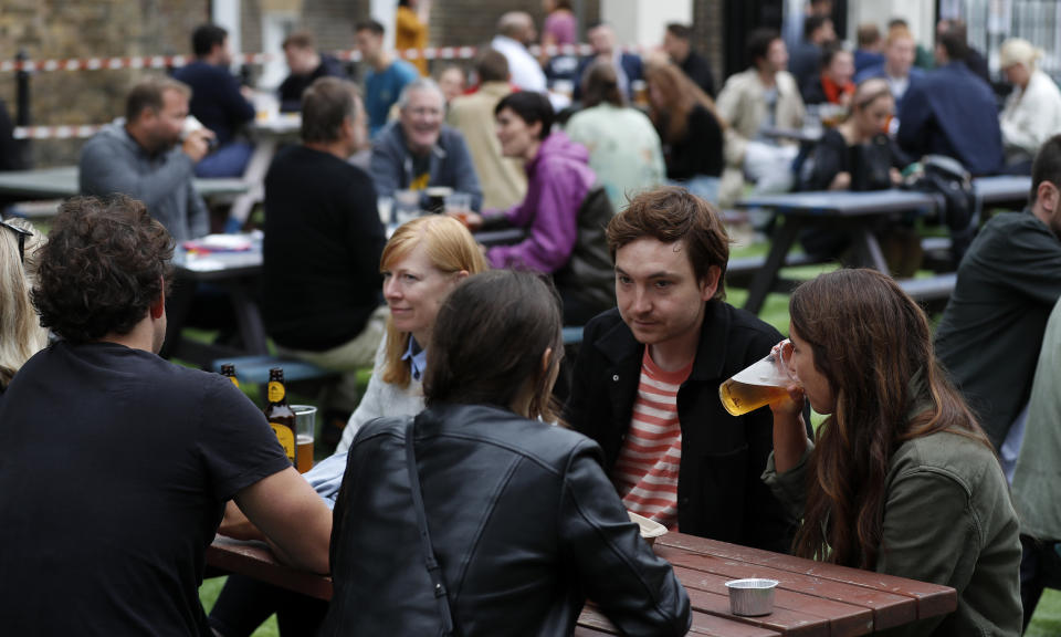 People enjoy their drinks at The Black Lion pub in London, Saturday, July 4, 2020. England is embarking on perhaps its biggest lockdown easing yet as pubs and restaurants have the right to reopen for the first time in more than three months. In addition to the reopening of much of the hospitality sector, couples can tie the knot once again, while many of those who have had enough of their lockdown hair can finally get a trim. (AP Photo/Frank Augstein)