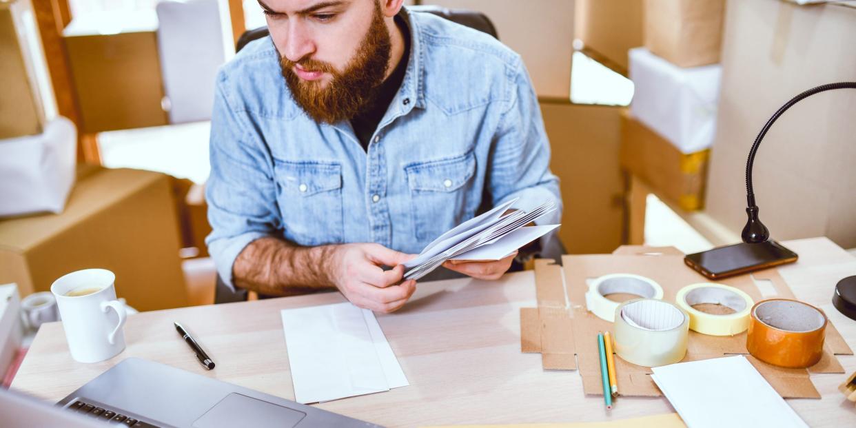 man mailing packages envelopes with laptop