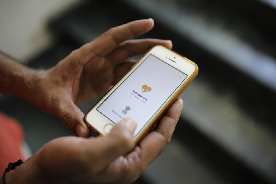 In this Thursday, May 7, 2020 photo, an Indian man uses Aarogya Setu app on his mobile phone in New Delhi, India. As India enters an extended coronavirus lockdown, the government is fervently pursuing contact tracing to control infections. At the heart of the effort in the country of 1.3 billion people is a smartphone app that evaluates users’ infection risk based on location services such as Bluetooth and GPS. (AP Photo/Altaf Qadri)