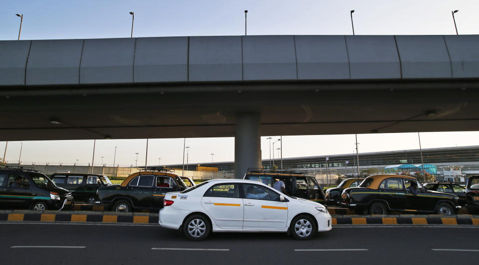 In this Wednesday, March 19, 2014 photo, an Uber taxi drives past traditional black-and-yellow licensed cabs in New Delhi, India. Riding on its startup success and flush with fresh capital, taxi-hailing smartphone app Uber is making a big push into Asia. The company has in the last year started operating in 18 cities in Asia and the South Pacific including Seoul, Shanghai, Bangkok, Hong Kong and five Indian cities. (AP Photo/Saurabh Das)