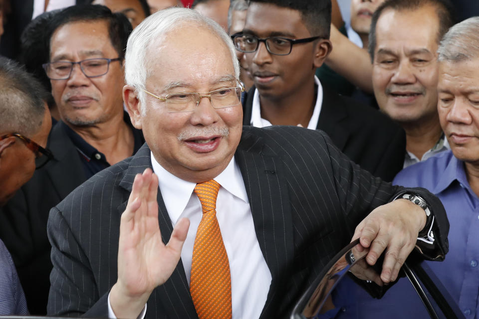 FILE - Former Malaysian Prime Minister Najib Razak, center, waves as he leaves Kuala Lumpur High Court in Kuala Lumpur on Nov, 19, 2019. Malaysia’s Appeal Court on Wednesday, Dec. 8, 2021, upheld the conviction of ex-Prime Minister Najib Razak linked to the massive looting of the 1MDB state investment fund that brought down his government in 2018. (AP Photo/Vincent Thian, File)