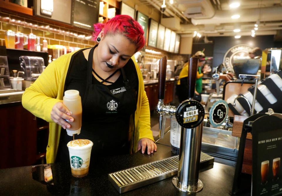 A Starbucks barista puts caramel sauce on a drink.