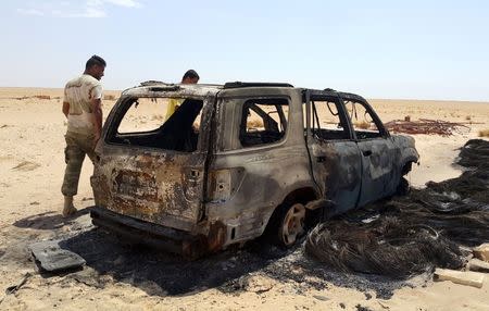 Men inspect the wreckage of a vehicle following clashes between forces loyal to eastern Libyan commander Khalifa Haftar and Benghazi Defence Brigades (BDB), an Islamist-leaning armed group, in the Magrun area, south of Benghazi, Libya July 21, 2016. Picture taken July 21, 2016. REUTERS/Stringer