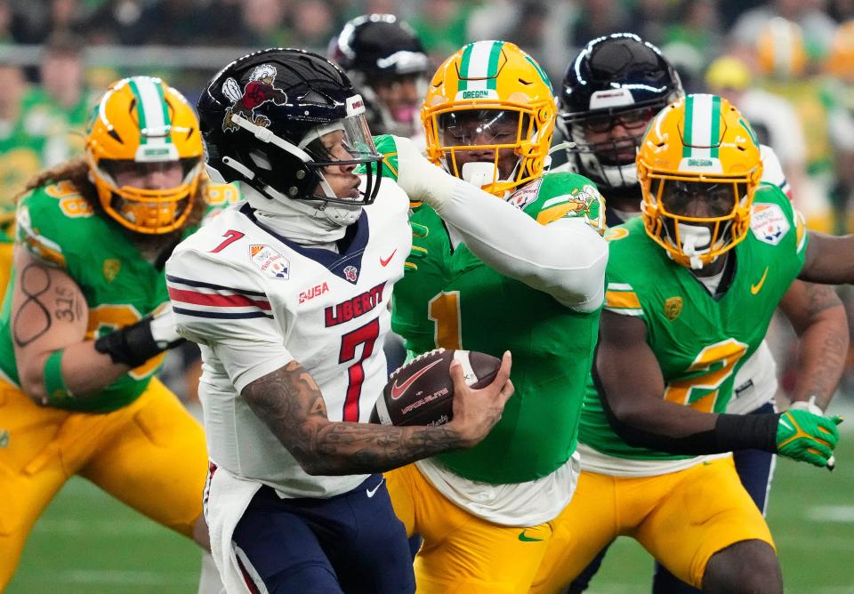 Liberty Flames quarterback Kaidon Salter (7) is chased by Oregon Ducks defensive end Jordan Burch (1) in the first half during the Fiesta Bowl at State Farm Stadium in Glendale on Jan. 1, 2024.